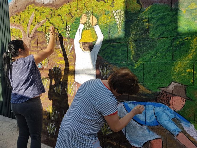 Participantes del taller pintan en un mural 