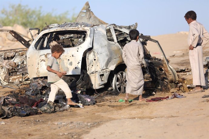 Niños yemeníes junto a los restos de un coche alcanzado por un ataque aéreo
