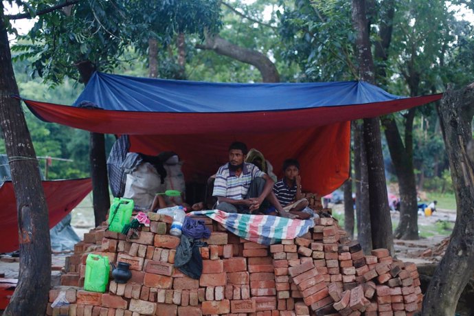 Refugiados rohingyas sentados sobre varios ladrillos de nueva construcción 