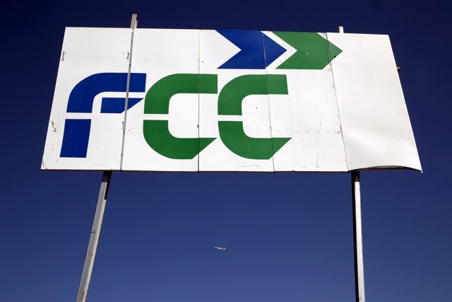 A plane flies past a sign of Spanish building and services group FCC in Tres Can