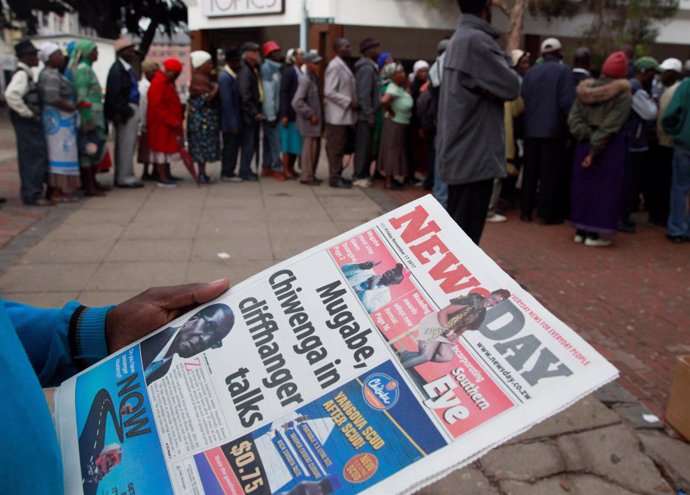Hombre lee un periódico en Zimbabue con Mugabe en la portada