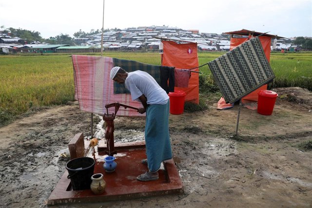 Un refugiado rohingya extrae agua junto a unos baños