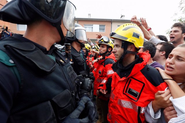 Firemen and people face off Spanish Civil Guard officers outside a polling stati