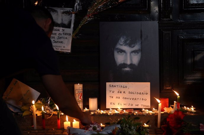 A man lights candles next to a portrait of Santiago Maldonado, a protester who w