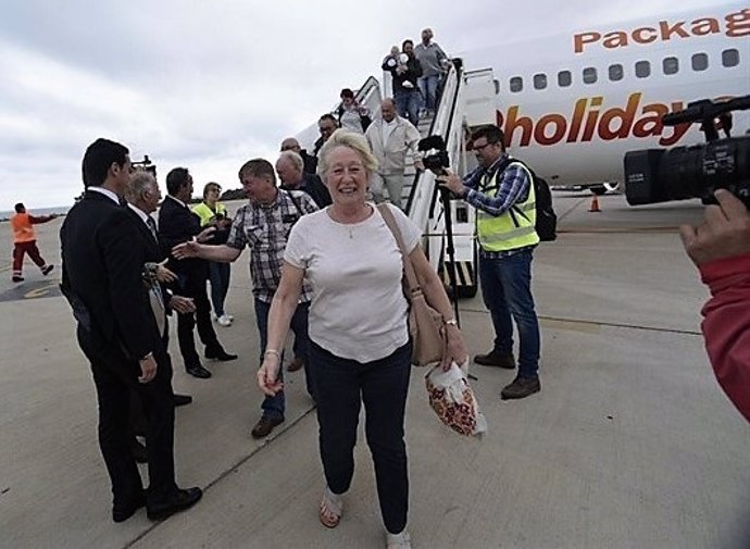 Turistas bajando de avión en aeropuerto