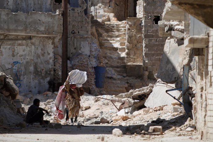 Mujer camina entre edificios destruidos en Alepo (Siria)