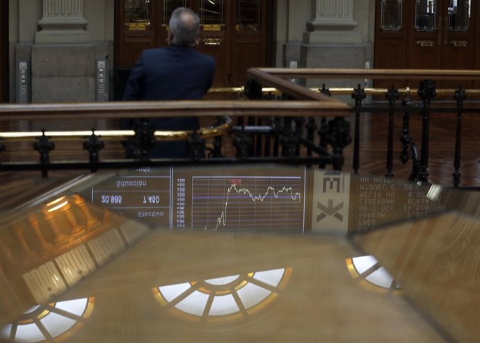 A trader talks on the phone as he looks at an index screen at Madrid's Bourse Oc
