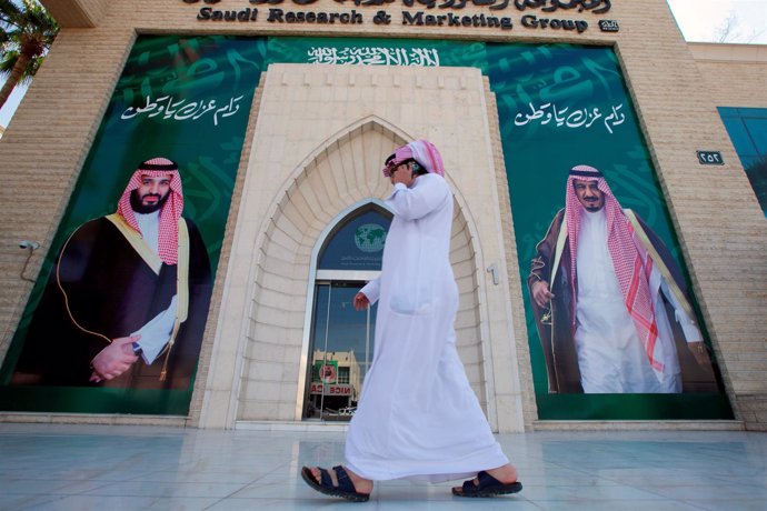 Un hombre frente a carteles del rey Salman y el príncipe heredero