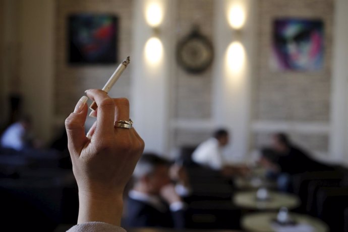 Una mujer sostiene un cigarrillo en una cafetería de Viena