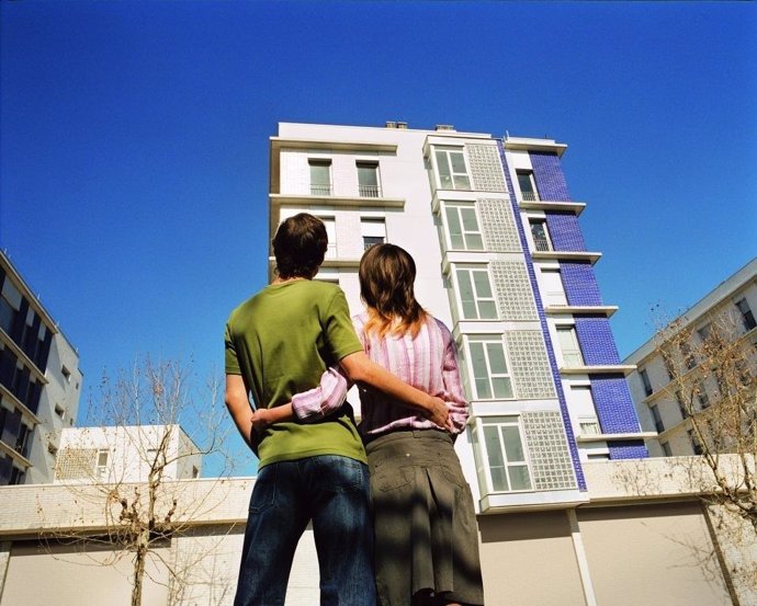 Jóvenes mirando un edificio de viviendas