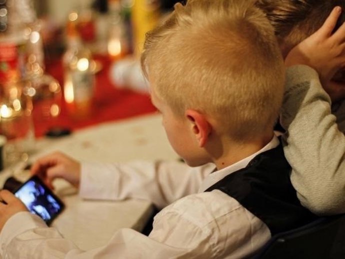 Niño con un teléfono en una comida familiar