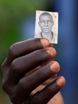 Un refugiado sursudanés muestra la foto de su hijo asesinado