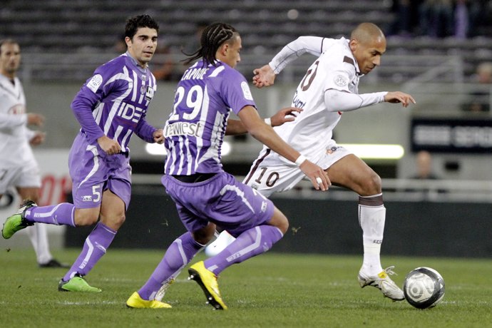 Toulouse's Luan Michel Louza (L) and Etienne Capoue (C) vie for the ball with Ju