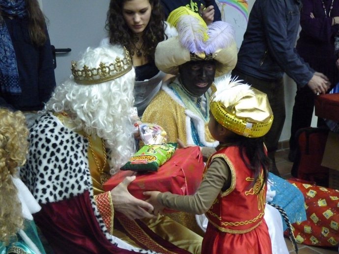 Una niña recibe su regalo de Reyes de manos del Rey Melchor