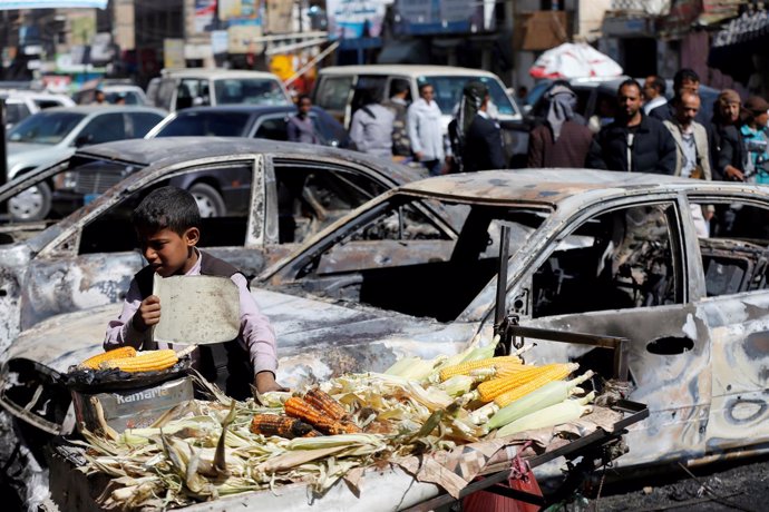 Un niño junto a coches destruidos en los combates en Saná