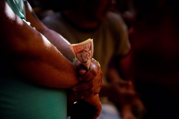 Un cubano sostiene un fajo de billetes