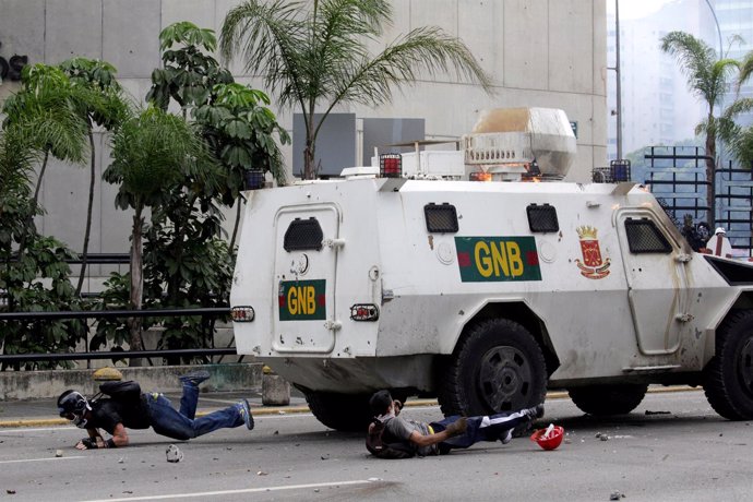 Manifestantes en suelo tras ser golpeados por un vehículo blindado en Caracas