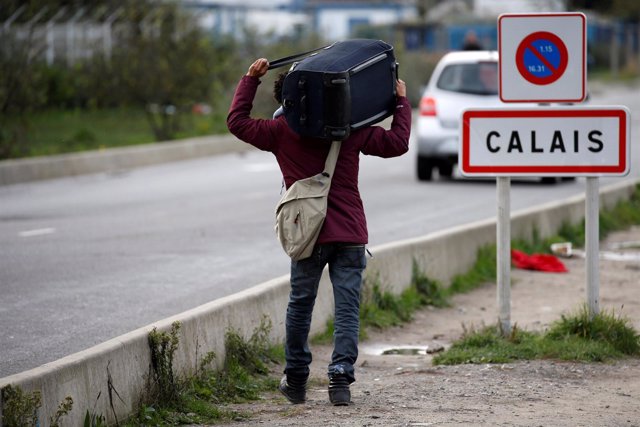 Un migrante lleva sus pertenencias en Calais