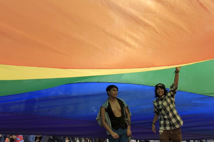 Dos manifestantes bajo una bandera arcoiris en Costa Rica.