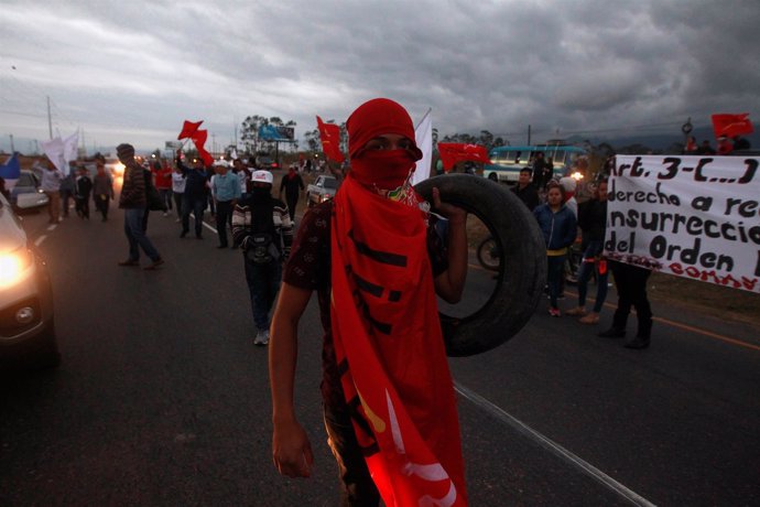 An opposition supporter carries a tire holds a during a protest against the re-e