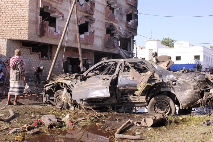 Un hombre junto a los restos de un coche bomba en Adén