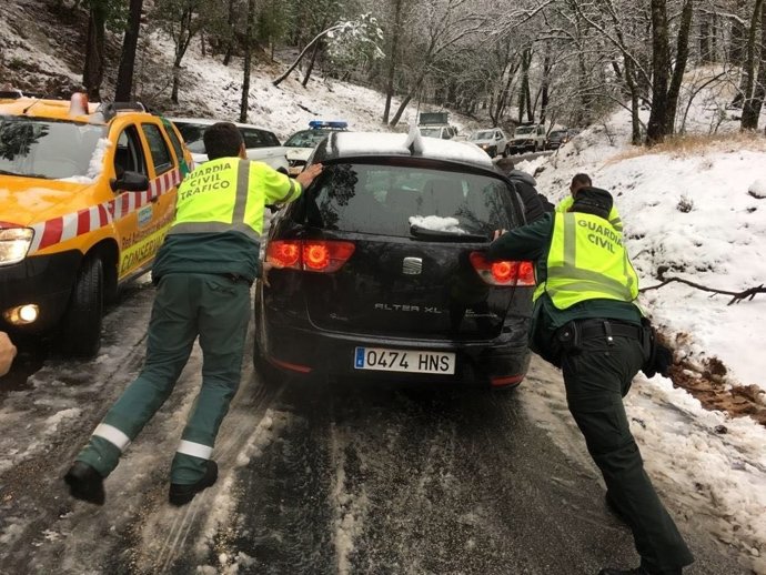Dos agentes ayudan a un coche a proseguir su marcha en el Puerto de las Palomas.