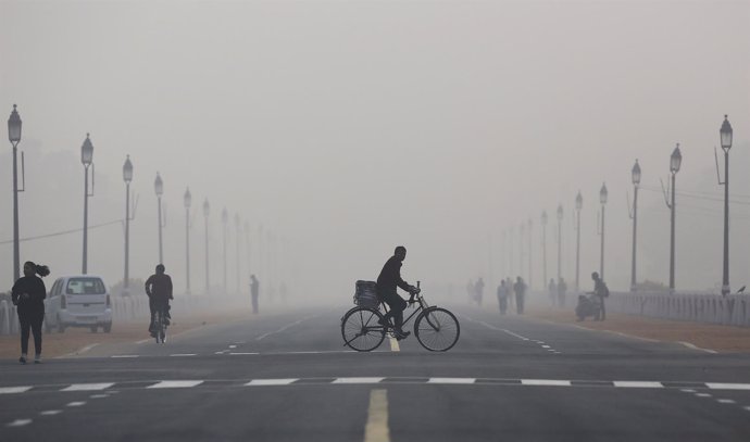 Hombre en bicicleta en Nueva Delhi en medio de la contaminación