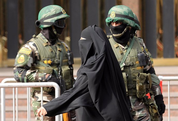Una mujer egipcia con velo pasa junto a soldados de las fuerzas especiales