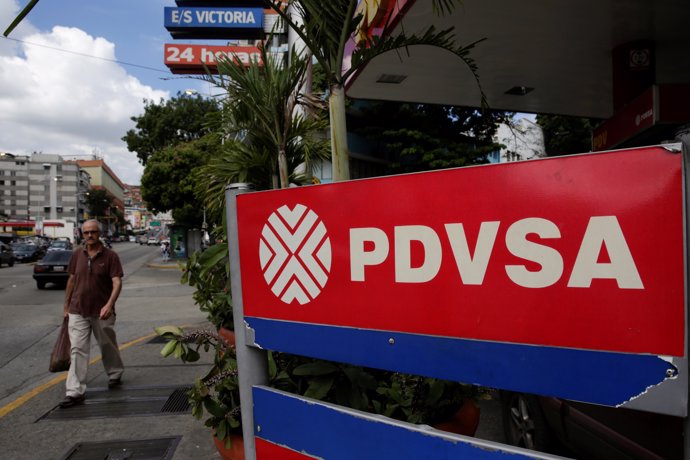 A man walks past the corporate logo of the state oil company PDVSA at a gas stat