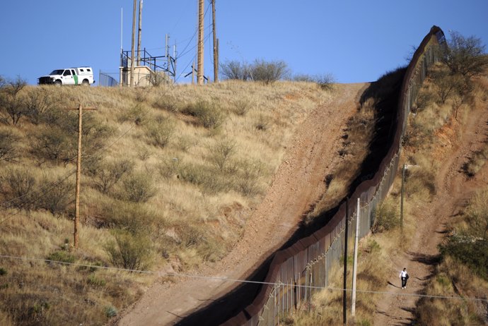 A woman walks near the border fence between Mexico and the United States in Noga