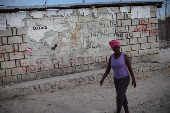 Una mujer delante de un cartel de Oxfam en un campo para desplazados en Haití