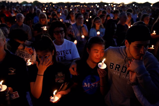 People attend a candlelight vigil for victims of yesterday's shooting at nearby 