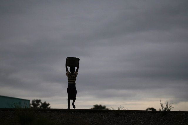 Un niño transporta agua recogida de un pozo comunal en Malaui