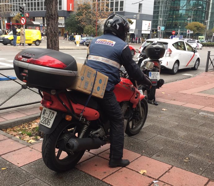 Un hombre trabaja con su moto llevando paquetes