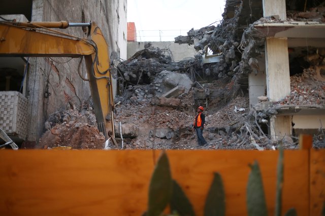 An employee works at a site where a building is demolished, five months after th