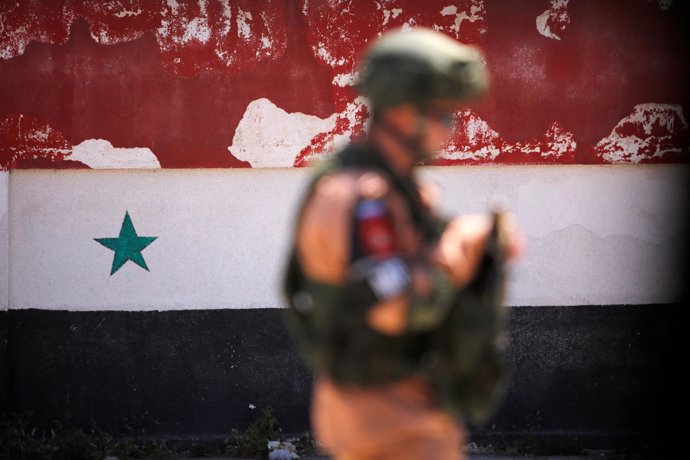 Un soldado ruso junto a una bandera nacional siria en la ciudad siria de Homs