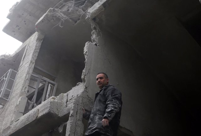 A man inspects damages on a building in the besieged town of Douma, eastern Ghou