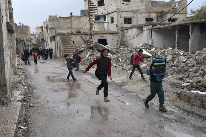 Niños junto a edificios destruidos en Deraa