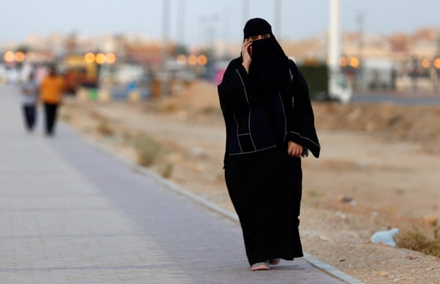 Una mujer saudí habla por teléfono mientras camina en una calle de Riad