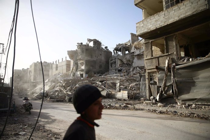 Un niño cerca de edificios dañados en la ciudad sitiada de Duma (Siria)