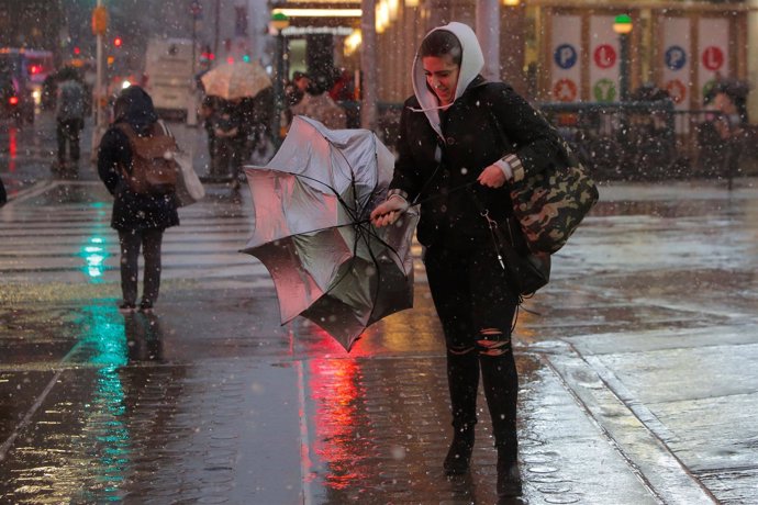 Una mujer lucha contra el viento con un paraguas