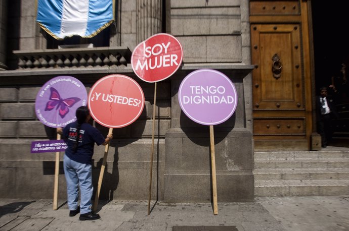 A Guatemalan woman places signs outside the Congress building during a protest a