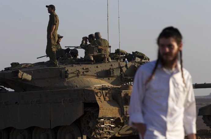 Un ultraortodoxo o haredi junto a un carro de combate israelí