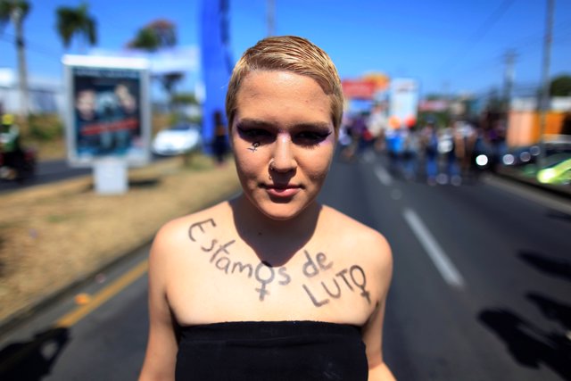 An activist with the phrase "We are in Mourning" written over her body takes par