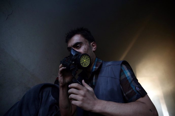 Un miembro de la defensa civil respira a través de una máscara