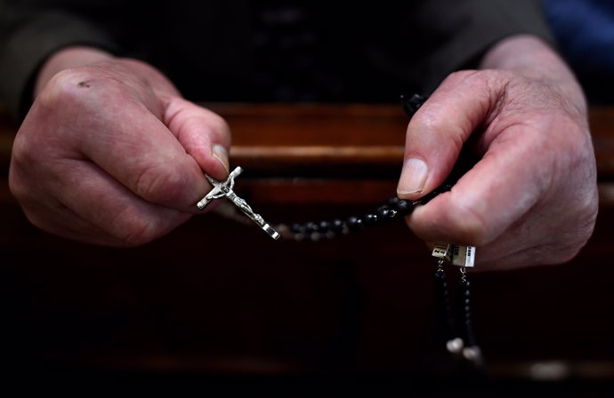 A worshipper holds rosary beads as Catholic Priest Pat McHugh conducts a mass to