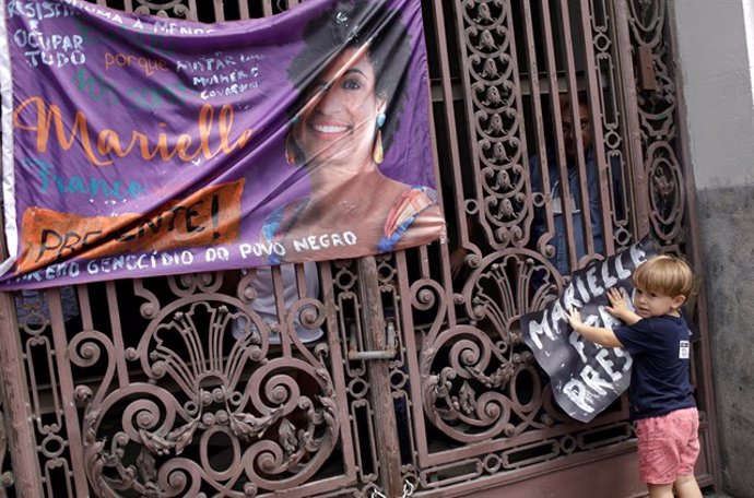Un niño coloca un cartel de protesta por el asesinato de Marielle Franco