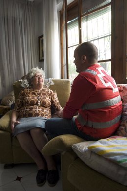 Voluntario de Cruz Roja atiende a una persona mayor