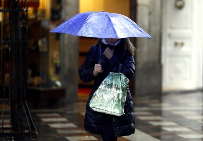 Una mujer sostiene un paraguas bajo la lluvia