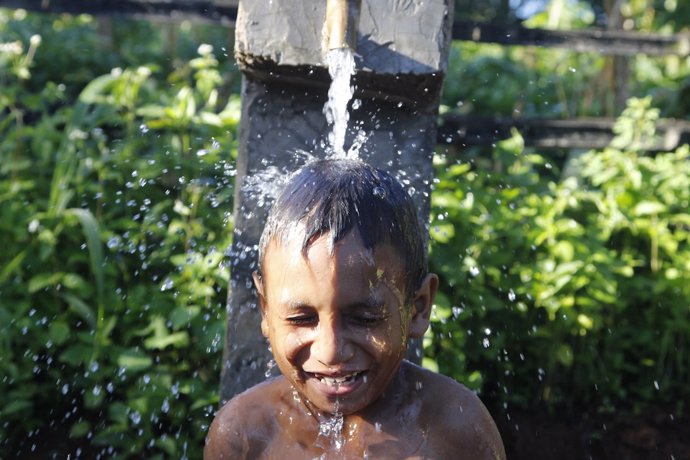 Niño se baña en un grifo público en Timor Oriental